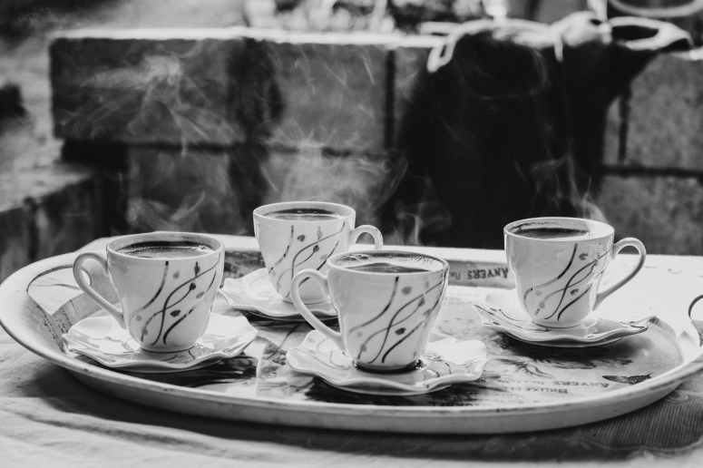 grayscale photography of ceramic mugs on saucers